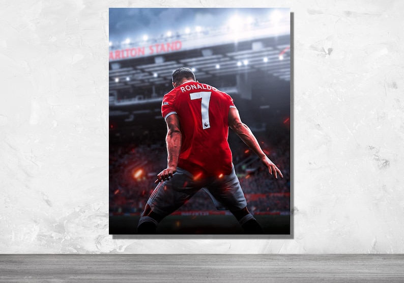 Op de afbeelding: Een voetballer draagt ​​een rood shirt met nummer 7 en de naam "RONALDO" op de rug. De speler staat op een voetbalveld met een menigte mensen op de achtergrond. Het stadion is verlicht met lichten.