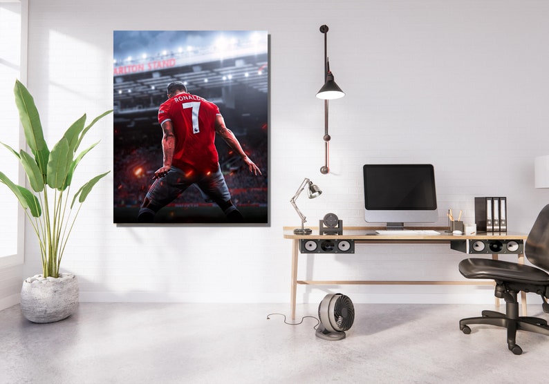 Op de afbeelding: Een professionele voetballer die een rood shirt draagt met nummer 7 en de naam "RONALDO" op de rug, viert een doelpunt in een stadion. De speler staat met zijn rug naar de camera, met de stadionverlichting en de menigte zichtbaar op de achtergrond.