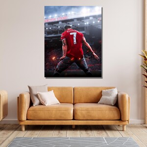 Op de afbeelding: Een voetballer in een rood shirt met nummer 7 en de naam "Ronaldo" op de rug viert een doelpunt in een stadion. De speler staat met zijn rug naar de camera en heeft zijn armen in de lucht gestoken.