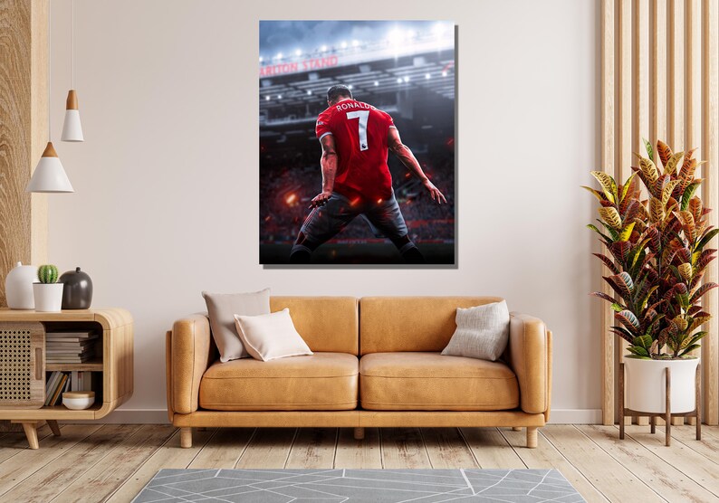 Op de afbeelding: Een voetballer in een rood shirt met nummer 7 en de naam "Ronaldo" op de rug viert een doelpunt in een stadion. De speler staat met zijn rug naar de camera en heeft zijn armen in de lucht gestoken.