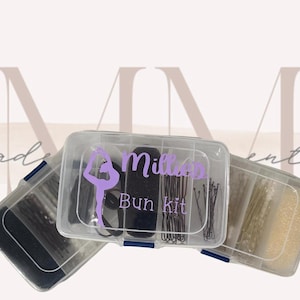 Puede incluir: Un recipiente de plástico transparente con tres compartimentos llenos de accesorios para el cabello. El compartimento del medio tiene una liga para el cabello negra y una silueta morada de una bailarina con el texto "Milla's Bun Kit".