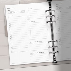 May include: A daily planner with a white background and black text. The planner has sections for daily tasks, priorities, a checklist, and notes. The planner is bound with silver rings.