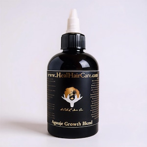 May include: A black bottle of hair care product with a white nozzle. The label features gold text that reads "www.HealHairCare.com" and "Aguanje Growth Blend". A gold illustration of a person's hair is also on the label.