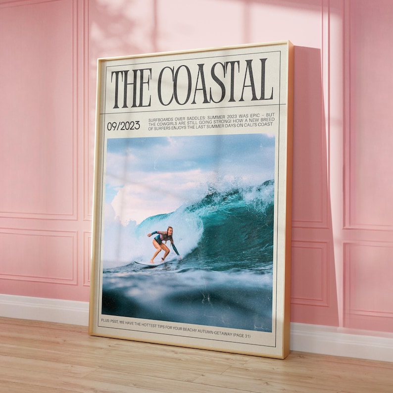 May include: Framed poster titled "THE COASTAL" with a surfing theme. The image features a surfer riding a large wave. The poster includes the date "09/2023" and text about surfing. The frame is gold-colored, and the background is pink.