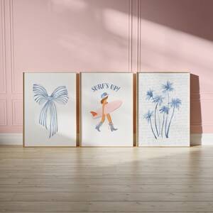 May include: Three framed prints with a blue and white bow, a woman in a blue hat and pink swimsuit holding a surfboard with the text "Surf's Up!" and a cluster of blue palm trees.