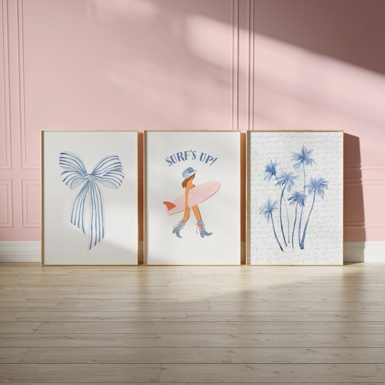 May include: Three framed prints with a blue and white bow, a woman in a blue hat and pink swimsuit holding a surfboard with the text "Surf's Up!" and a cluster of blue palm trees.