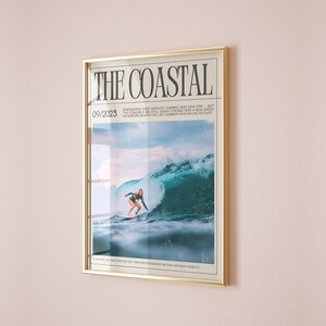 May include: Framed print titled "THE COASTAL" with a gold frame. The image features a surfer riding a large wave. The text "09/2023" is visible, along with additional text about surfing. The overall theme is surfing and coastal lifestyle.