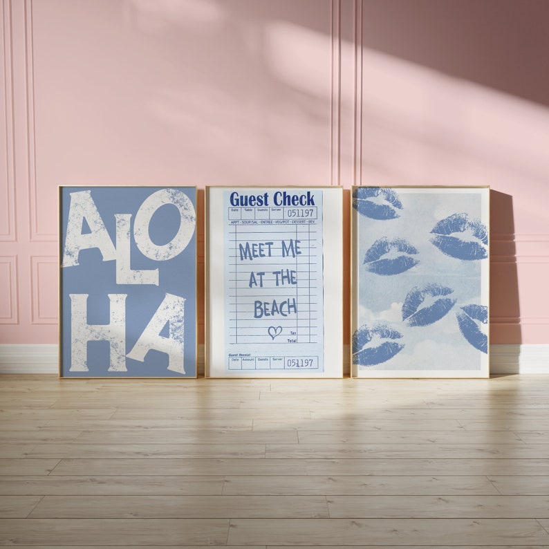 May include: Three framed prints with a blue background. The left print says "ALOHA" in white letters. The middle print is a guest check with the text "Meet me at the beach" and a heart symbol. The right print has a blue sky background with multiple blue lips printed on it.