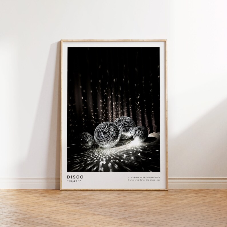 May include: A black and white poster with the word "DISCO" in white text and the phonetic spelling "/ˈdɪskoʊ/" below it. The poster features a photo of several disco balls reflecting light in a dark room.