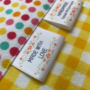 May include: Two white satin fabric labels with floral designs and black text. The top label reads "Handmade Cassie McCormack". The bottom label reads "Made with Love".