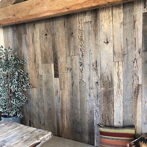May include: A wall covered in vertical reclaimed wood planks with a natural weathered gray and brown finish, featuring visible wood grain, knots, and texture, topped by a large horizontal wooden beam across the upper section.