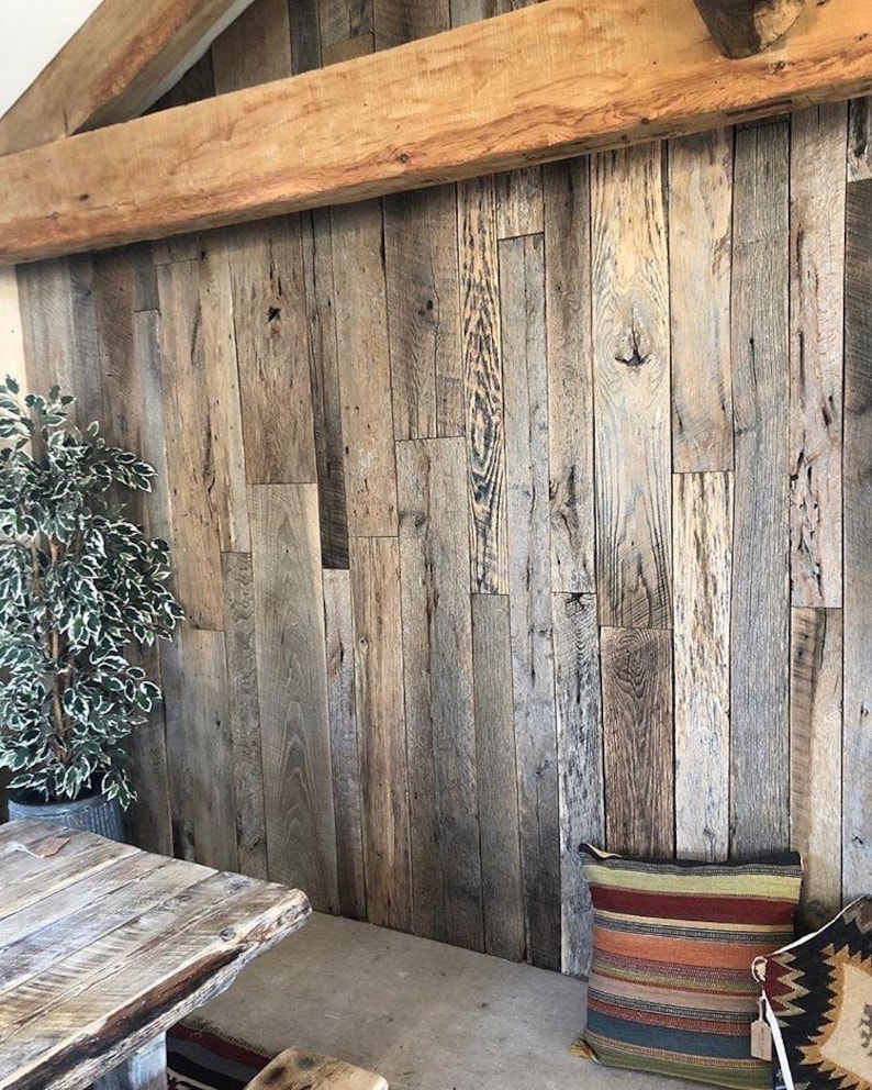 May include: A wall covered in vertical reclaimed wood planks with a natural weathered gray and brown finish, featuring visible wood grain, knots, and texture, topped by a large horizontal wooden beam across the upper section.