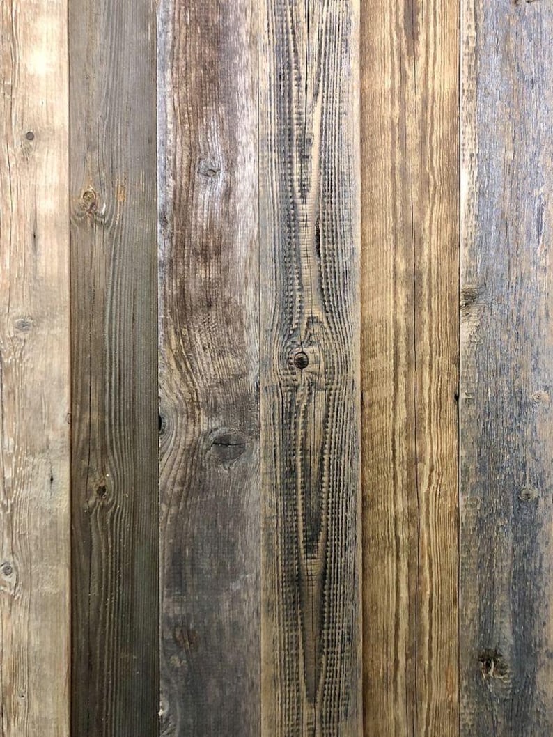 May include: A collection of vertical wooden planks featuring a weathered texture with visible grain patterns, knots, and a color palette ranging from light beige and tan to dark gray and brown tones, creating a rustic, multi-tonal surface.