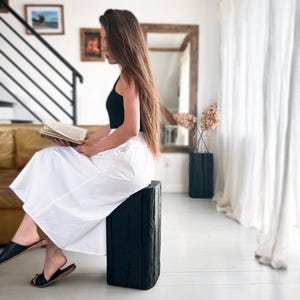 May include: A black sleeveless top paired with a long, flowing white skirt. The outfit is completed with simple black slide sandals. The skirt features a clean, solid white fabric with a full silhouette that reaches below the knees.