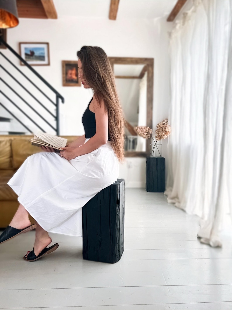 May include: A black sleeveless top paired with a long, flowing white skirt. The outfit is completed with simple black slide sandals. The skirt features a clean, solid white fabric with a full silhouette that reaches below the knees.