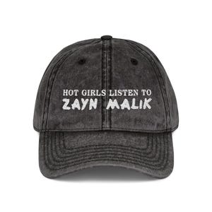 May include: A distressed black baseball cap with the text "HOT GIRLS LISTEN TO ZAYN MALIK" embroidered in white. The cap has a curved brim and an adjustable strap.