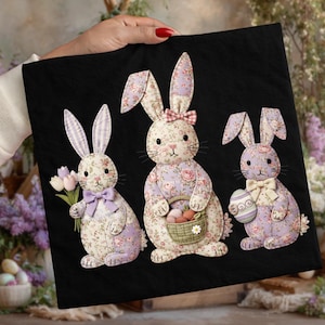 Könnte beinhalten: Drei Osterhasen-Dekorationen auf schwarzem Hintergrund. Die Hasen sind aus Stoff mit floralen Mustern in Rosa, Lila und Weiß gefertigt. Ein Hase hält einen Tulpenstrauß, ein anderer einen Korb mit Karotten und der letzte ein Osterei.