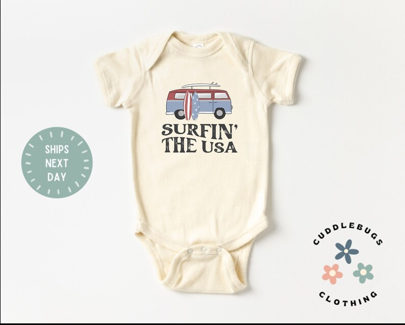 May include: A cream-colored baby onesie with a vintage-style illustration of a blue and red van with surfboards on top. The text "Surfin' The USA" is printed in brown below the van.