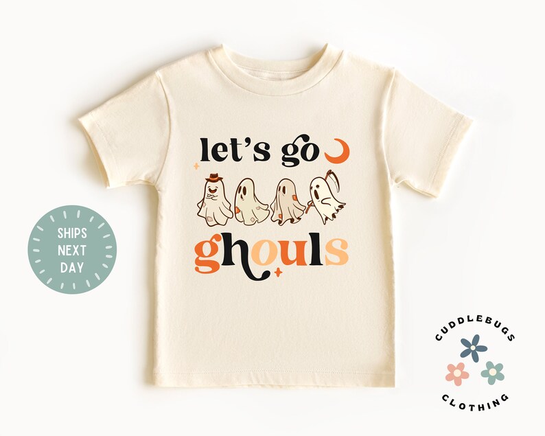 K&ouml;nnte beinhalten: Ein cremefarbenes T-Shirt mit einer Grafik von Geistern und dem Text "Let's go ghouls".