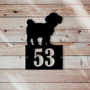 Può includere: Cartello di numero civico in metallo nero con la silhouette di un piccolo cane in piedi sul numero "53".