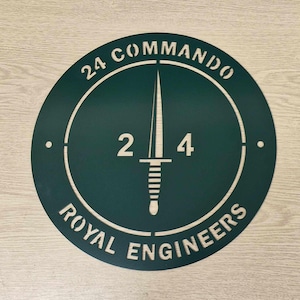 May include: A round, green metal sign with the text "24 Commando Royal Engineers" and a stylised dagger in the centre. The number "24" is displayed above the dagger.