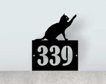 May include: Black metal house number sign with the number 339 and a silhouette of a cat reaching up with its paw.