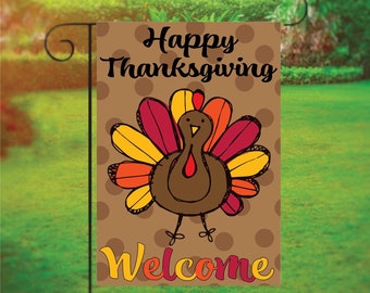 May include: A brown garden flag with a cartoon turkey with a red wattle and a yellow, orange, and red tail. The flag has white polka dots on a brown background and the text "Happy Thanksgiving" and "Welcome" in yellow and orange letters.