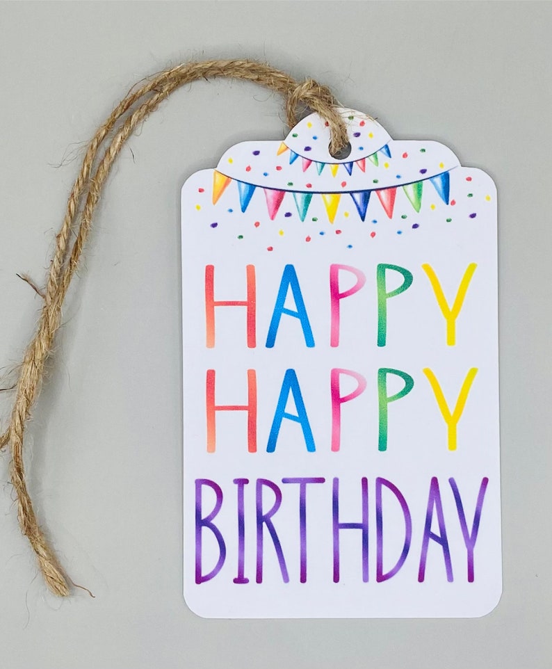 May include: A white gift tag with a colourful happy birthday message. The tag has a rainbow design with confetti and a string of flags. The tag is tied with a brown twine string.
