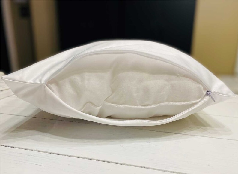 May include: A white pillowcase with a zipper closure. The pillowcase is made of a soft, smooth fabric.
