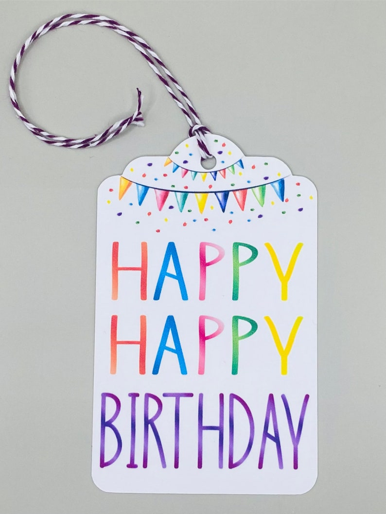 May include: A white gift tag with a colourful rainbow design. The tag has a string attached and says "Happy Happy Birthday" in a rainbow font.