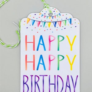 May include: A white gift tag with a colourful rainbow design. The tag has a string attached and says "Happy Happy Birthday" in rainbow letters.
