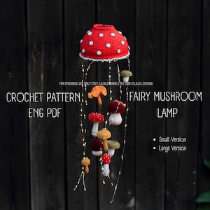 May include: A handmade crochet fairy mushroom lamp with a red cap and white polka dots. The lamp has a white trim and is adorned with several smaller crochet mushrooms in various colors. The text "CROCHET PATTERN" and "FAIRY MUSHROOM LAMP" are visible.