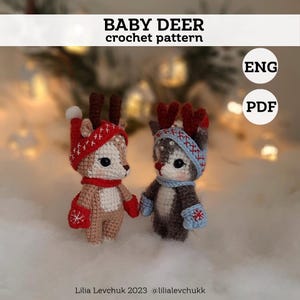 Op de afbeelding: Haakpatroon voor een babyhert, met twee schattige herten die rode en blauwe mutsen en wanten dragen. Het patroon is beschikbaar in het Engels en in PDF-formaat.