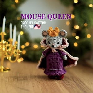 May include: A crocheted mouse doll wearing a yellow crown, a purple dress, and a dark red cape with a light pink trim. The text MOUSE QUEEN CROCHET PATTERN ENG PDF is visible above the mouse, along with a small US flag icon and a website URL.