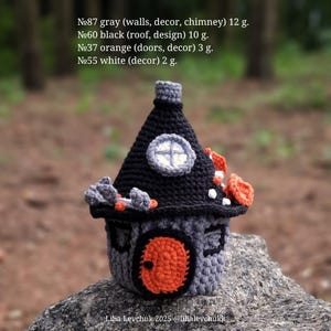 May include: A handcrafted crochet house in gray, black, and orange. The house features a black roof, an orange door, and a small round window. The text on the image reads: "№87 gray (walls, decor, chimney) 12 g. №60 black (roof, design) 10 g. №37 orange (doors, decor) 3 g. №55 white (decor) 2 g."