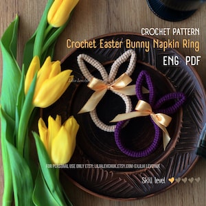 Może przedstawiać: Dwa szydełkowe pierścienie na serwetki w kształcie zajączka wielkanocnego, beżowy i fioletowy, każdy ze złotą wstążką. Obraz zawiera żółte tulipany i tekst "CROCHET PATTERN Crochet Easter Bunny Napkin Ring ENG PDF".