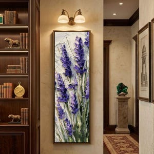 May include: A framed vertical painting of lavender flowers in shades of purple and green against a white textured background. The artwork is displayed in a hallway with a warm color palette, complemented by a decorative light fixture.