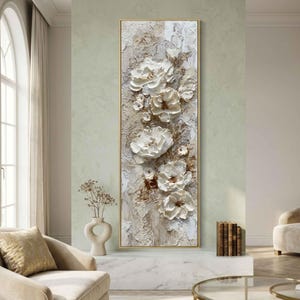 May include: A vertical rectangular canvas art piece featuring textured white flowers with brown centers against a neutral background. The artwork is framed in a gold-colored border, creating a three-dimensional effect.