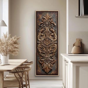May include: A framed, rectangular wall art piece with a detailed, ornate, gold-colored relief design. The relief features swirling patterns and floral motifs against a textured, dark background. The frame is a warm, neutral tone.