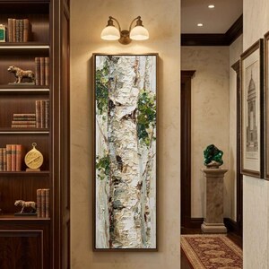 May include: Vertical framed artwork featuring a textured painting of birch tree trunks. The bark is primarily white with areas of beige and brown, accented by green foliage. The artwork is displayed in a hallway with a bookshelf and decorative lighting.
