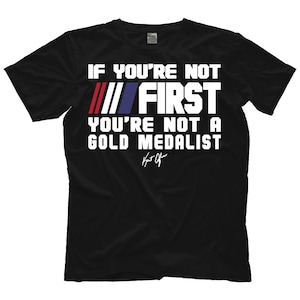 Puede incluir: Camiseta negra con texto blanco que dice "Si no eres el primero, no eres un medallista de oro" con un patrón de rayas rojo, blanco y azul y una firma.