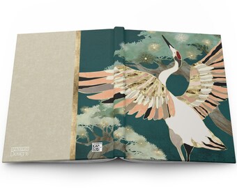 May include: An open book with a teal cover featuring a white crane with gold and peach accents. The crane is flying with its wings spread wide. The background is a dark teal with gold and green pine trees.