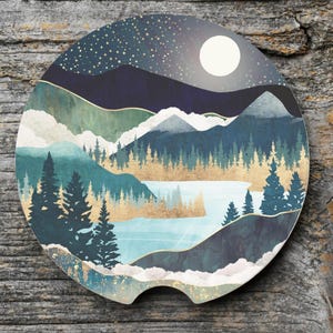 May include: Round car coaster featuring a mountain landscape design. The coaster has a night sky with a full moon and stars, with mountains, trees, and a lake in shades of blue, green, and gold.