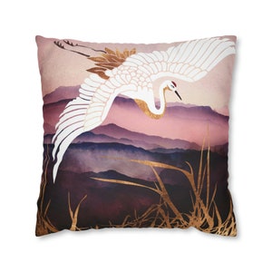May include: A white crane with gold accents flies over a purple and pink watercolor mountain landscape. The crane is in flight with its wings spread wide. The background is a soft, dreamy watercolor wash.
