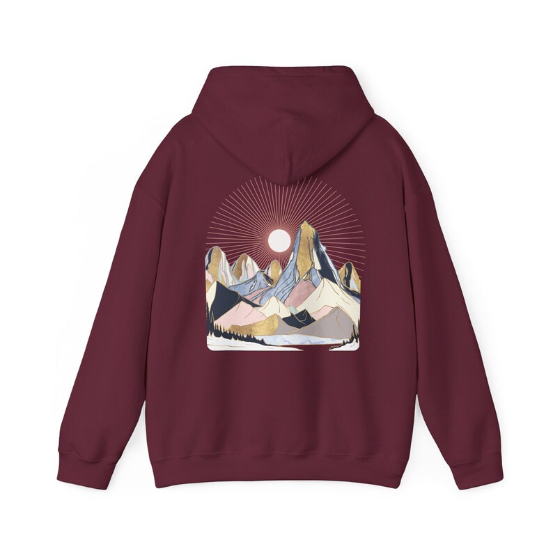 Pu&ograve; includere: Felpa con cappuccio bordeaux con grafica di catena montuosa e design a raggi di sole. L'illustrazione presenta montagne nei toni dell'oro, blu, rosa e grigio. La felpa ha un cappuccio e maniche lunghe.
