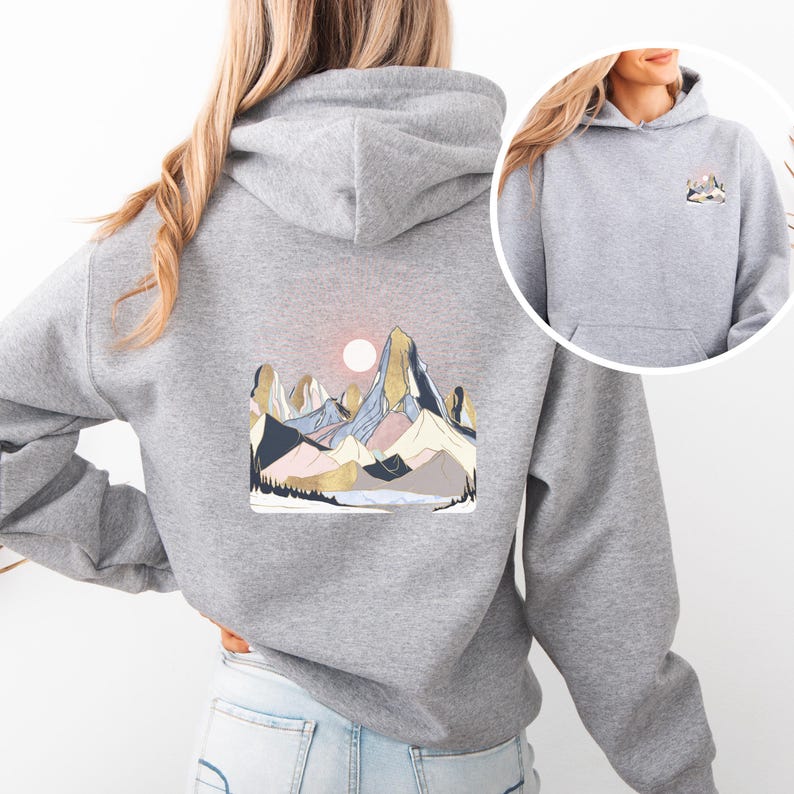 Pu&ograve; includere: Una felpa con cappuccio grigia con un disegno di paesaggio montano sul retro e una versione pi&ugrave; piccola sul davanti. Il disegno comprende un sole, montagne nei toni del blu, rosa e oro e una foresta alla base. La felpa ha una tasca frontale e un cappuccio.