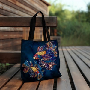 May include: A dark blue tote bag with a design of two colorful fish with long flowing fins. The fish are a mix of orange, red, blue, and gold.