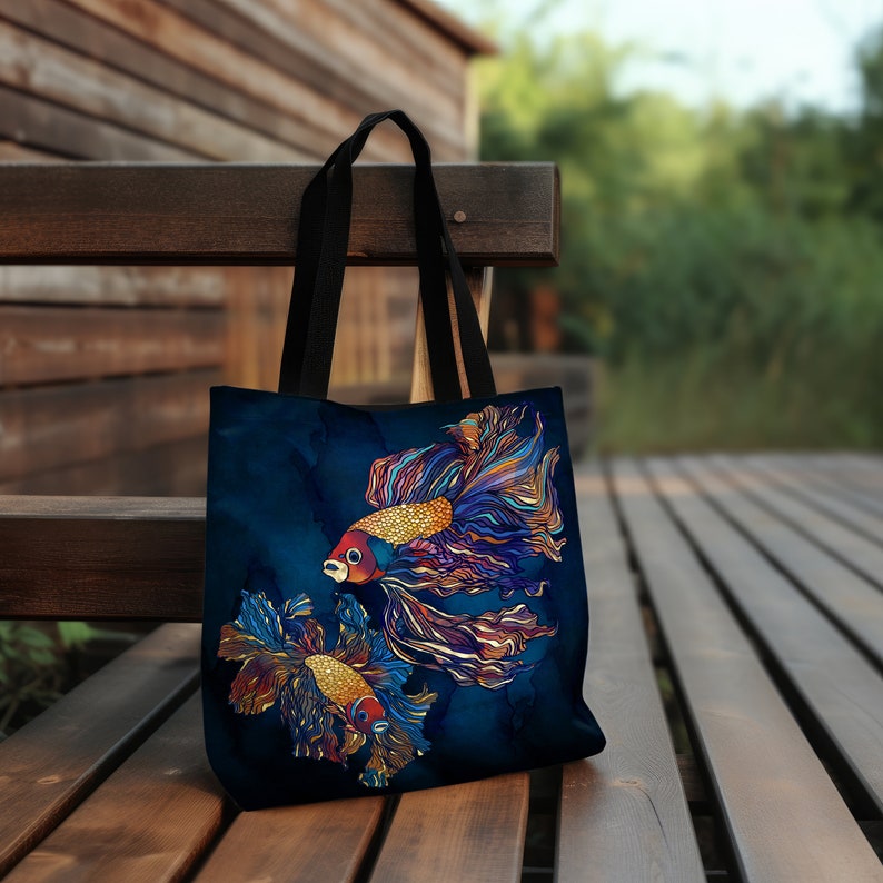 May include: A dark blue tote bag with a design of two colorful fish with long flowing fins. The fish are a mix of orange, red, blue, and gold.