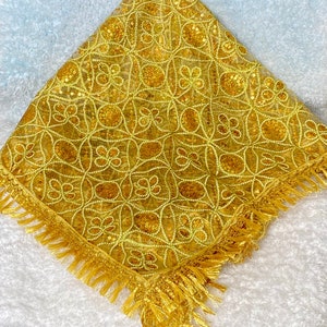 May include: A yellow square scarf with a gold embroidered floral pattern and gold fringe trim.
