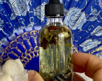 May include: A clear glass bottle with a black dropper top filled with a light yellow liquid and glitter. The bottle contains small white and brown objects.